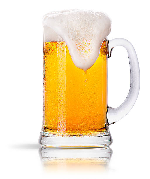 Glass mug of golden beer with foam spilling down the side stock photo
