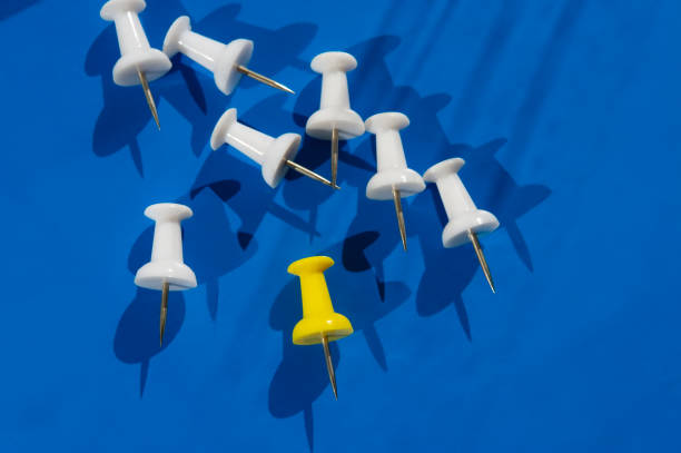 istock White pushpins and  one yellow on blue. 1787598834