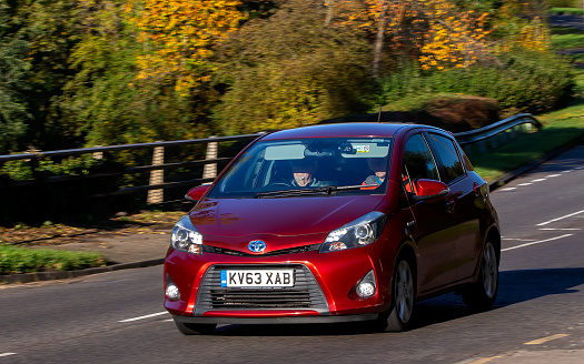 Milton Keynes,UK - Nov 11th 2023:  2013 red hybrid electric Toyota Yaris car driving on an English road