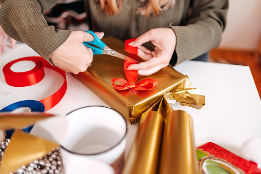 Young adult using scissors with preparing gift for New Years Eve