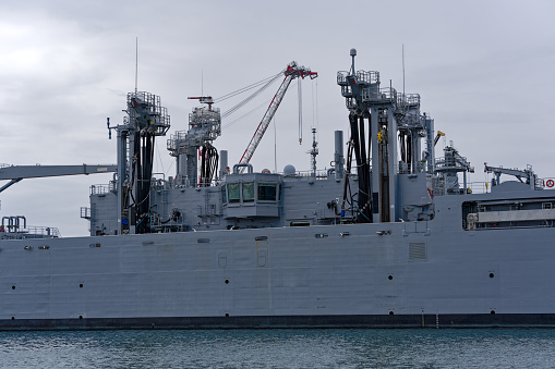 The communications masts and structures of HMAS Canberra are surrounded by scaffolding when docked at Garden Island naval base in Sydney Harbour.  She is one of two Canberra Class amphibious assault ships of Royal Australian Navy. This image was taken on an overcast and windy afternoon on 25 November 2023.