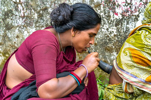 A nomadic gypsy healer from Bangladesh blows through her horn to cure a patient