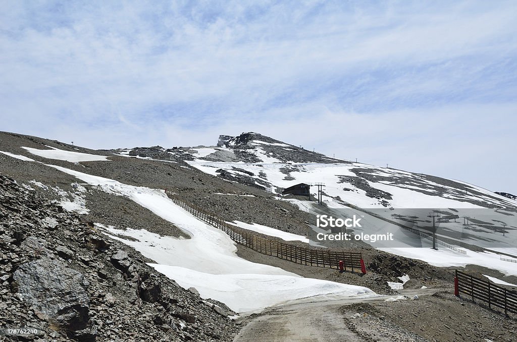 Spanish ski resort in spring, Veleta Andalusian Sierra Nevada is photographed at the Pradollano ski resort in spring. There are downhills with snowfields and an idle ski lift. In the background the famous peak Veleta is well within view. Andalucian Sierra Nevada Stock Photo