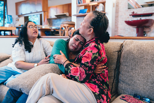 Love, family or comfort with a senior woman and daughter hugging in the living room of their home together. Support, care or trust with a mature mother and adult child bonding together in a house