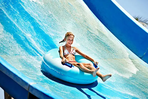 Child on water slide at aquapark. Summer holiday.