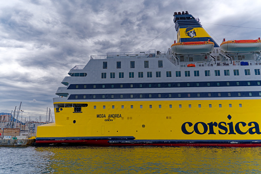 Yellow Corsica and Sardinia ferry named Mega Andrea moored at port of Toulon on a cloudy late spring day. Photo taken June 9th, 2023, Toulon, France.