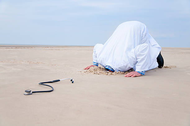 Doctor hiding head in sand Doctor hiding head in sand. In the front a stethoscope.have a look at different variations: head in the sand stock pictures, royalty-free photos & images