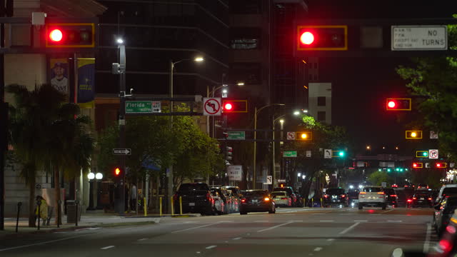 Urban road intersection with traffic lights and moving cars at night in American city. Transportation system in USA