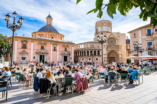 Valencia-Spain November 11, 2023. Cword of tourists enjoying a sunny day sitting in street cafe at Plaza de la Virgen or Plaça de la Mare de Déu