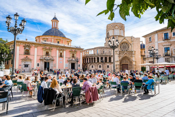 Tourists sitting at street cafe in Valencia, Spain Valencia-Spain November 11, 2023. Cword of tourists enjoying a sunny day sitting in street cafe at Plaza de la Virgen or Plaça de la Mare de Déu busy restaurant tables stock pictures, royalty-free photos & images