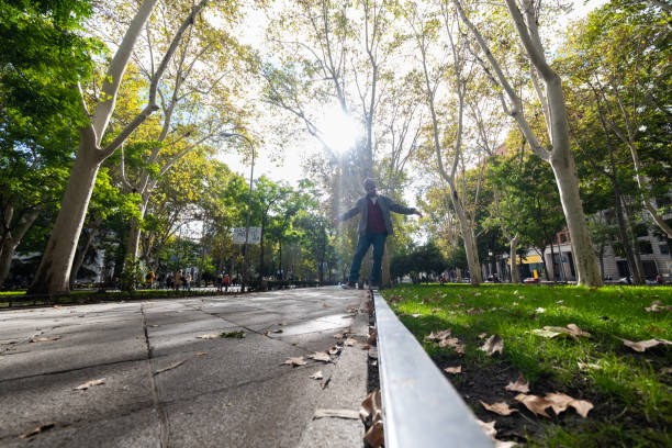 Bearded gent, wide-angle view, balances on Madrid's sunlit autumn sidewalk.