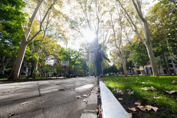 Urban equilibrium: Young man, wide-angle perspective, gracefully balances in Madrid's autumn.