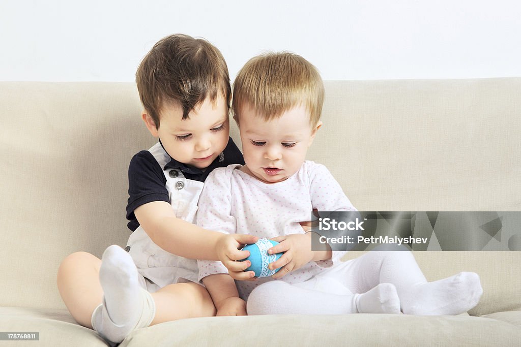 Little Friends two little boys sitting on couch and playing 12-17 Months Stock Photo