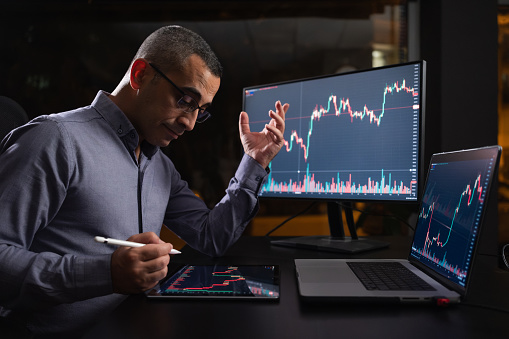 Tired Man Checking His Stock Market Exchange Investment Using His Laptop Computer At Night.