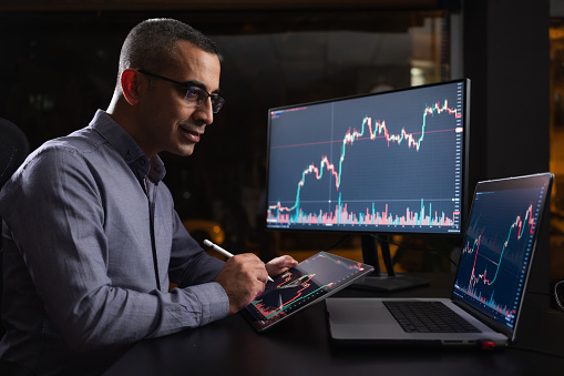 Man Checking His Stock Market Exchange Investment Using His Laptop Computer At Night.