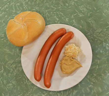 A visit to a simple inn in Vienna. A pair of Frankfurter sausages with mustard and horseradish and a roll. Typical table in the design of the 60s.