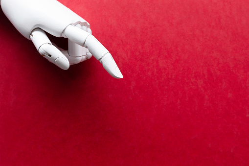 Pointing  white robot finger in front of red background.