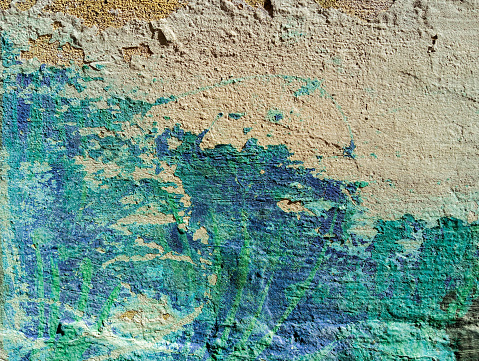 White peeling paint on the wall. Old concrete wall with cracked flaking paint.