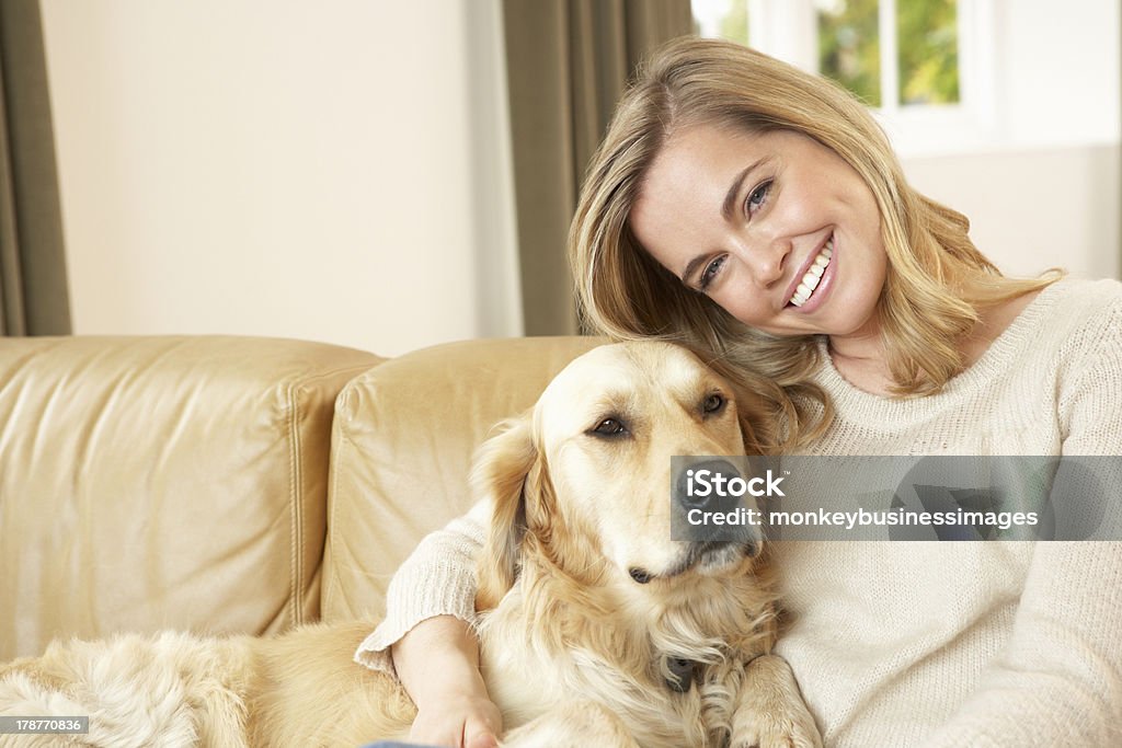 Young woman with dog sitting on sofa Young woman with dog sitting on sofa relaxing smiling to camera Dog Stock Photo