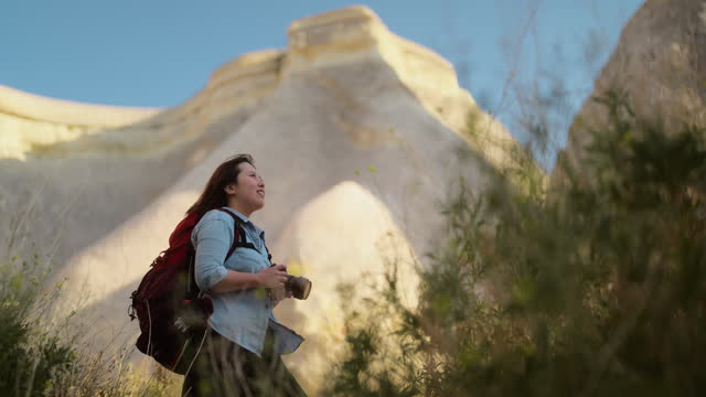 Portrait of beautiful Asian female tourist hiker photographer videographer with her camera in Cappadocia Türkiye Turkey