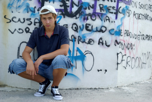 Boy sitting in front of graffiti wall