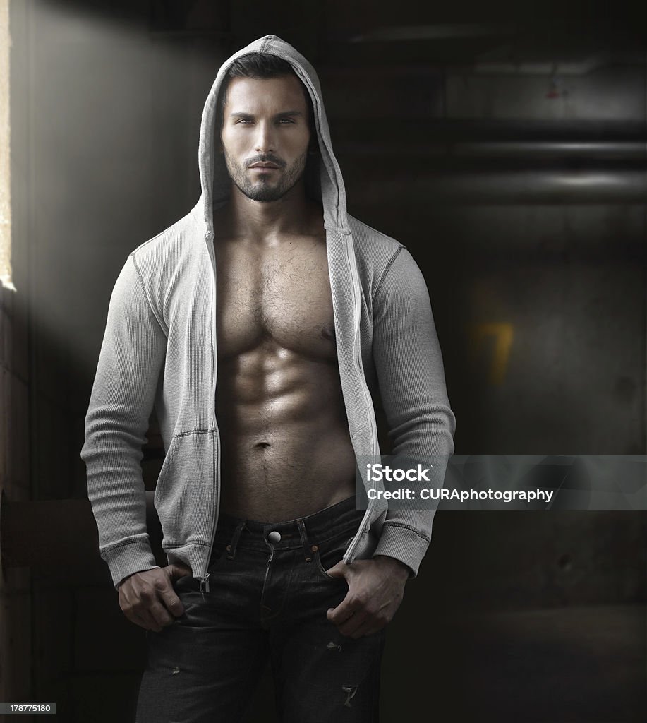 Sex man Young handsome macho man with open jacket revealing muscular chest and abs in industrial garage with window light Men Stock Photo