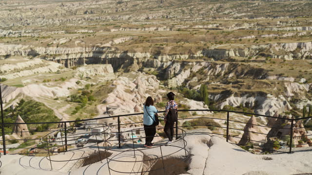 Two female tourist friends looking at view of Cappadocia from top of high hill