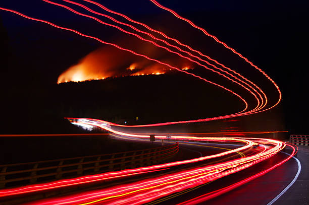 Lights of truck with trailer in the night passing by forest fire in British Colombia, Canada