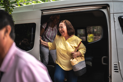 Traveler senior woman getting out of the van outdoors
