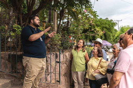 Private tourist guide explaining the place history to tourists outdoors