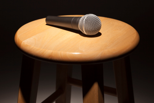 Microphone Laying on Wooden Stool Under Spotlight