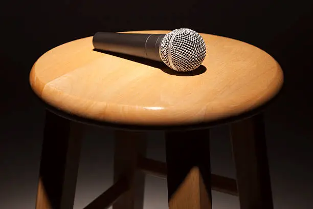 Photo of Microphone Laying on Wooden Stool Under Spotlight
