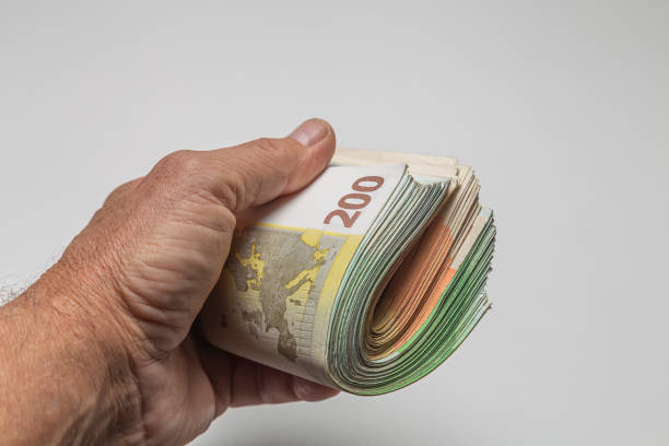istock Man's hand holding a bundle of euro banknotes on white background 1787780421