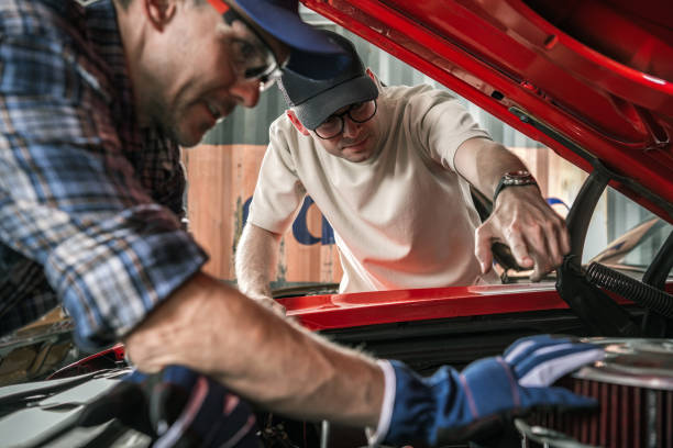 istock Classic Muscle Cars Enthusiasts Working on the Car Engine 1787783627