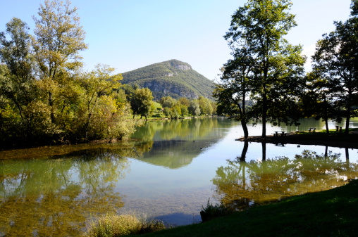 View of calm Sillingy lake in Savoy and reflection of trees and mountains- France
