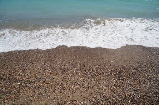 waves on mediterranean sea with pebble beach and green water