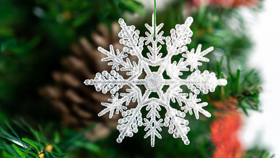 The Christmas tree branches, beautifully decorated with a white Xmas snowflake, setting a festive ambiance with the sparkling Christmas balls.