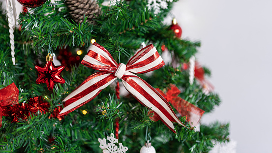 The Christmas tree branches are beautifully decorated with a Xmas red and white bow, setting a festive ambiance with the sparkling Christmas balls.