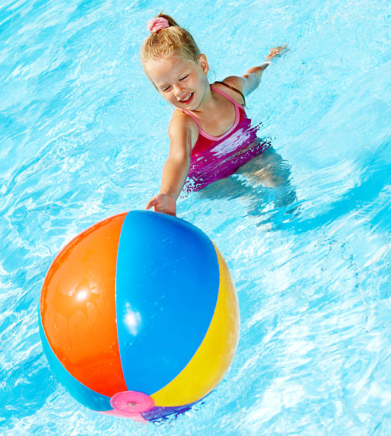 enfant assis sur anneau gonflable dans la piscine. - beach ball swimming pool ball child photos et images de collection