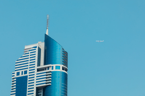 Dubai, United Arab Emirates - June 21, 2023: Dubai skyscrapers and flying Emirates Plane in the sky