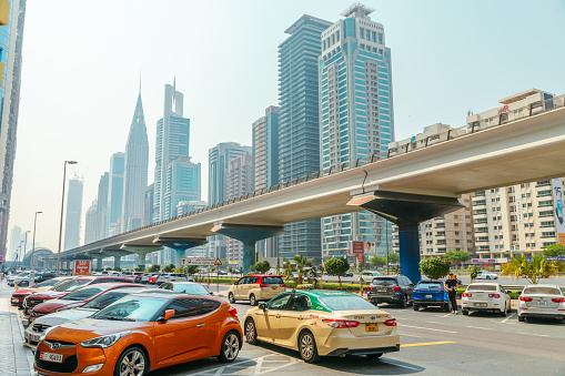 A view of a Dubai multiple lane highway, contemporary architecture in the background.  Skyscrapers,  Dubai cityscape. Clear sky, daytime, nobody, vehicles travelling, horizontal composition. 