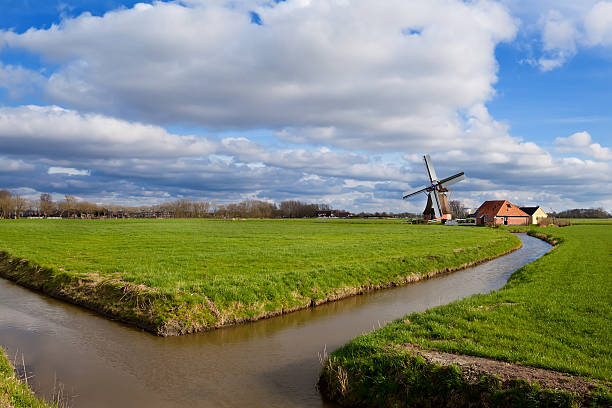 istock charming Dutch windmill on green grassland 178784835