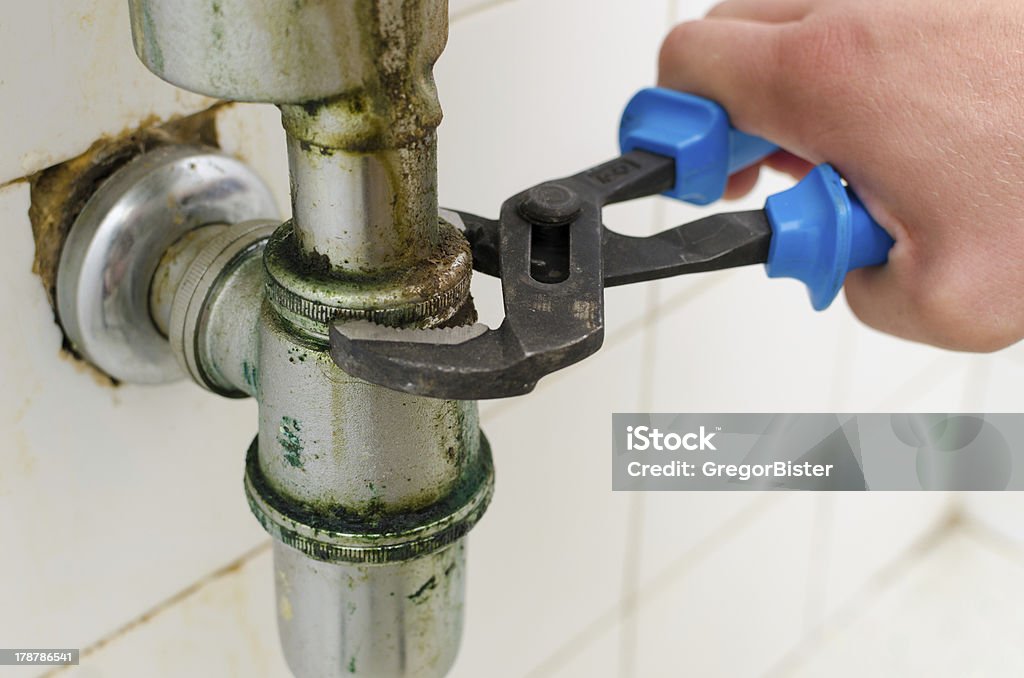 Plumber's Pipe Wrench A closeup of a plumber using a pipe wrench on a pipe. Sink Stock Photo