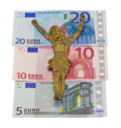 Gold jesus crucify on euro banknotes isolated on white. Concept of europe finance crisis. Five ten and twenty euro banknotes.