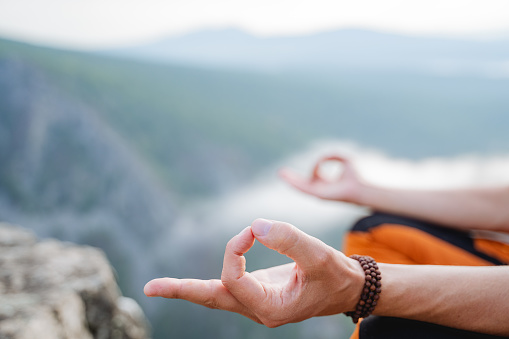Hands close-up fingers folded into chinmudra, wise for meditation, balance of the inner world, Zen practice in nature, silence of inhalation, bracelet on the arm. High quality photo