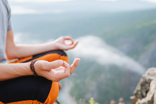 istock Hands fingers folded in mudra yogic practice, the guy meditates sitting in the mountains against the background of clouds, the silence of the inner world. 1787881055