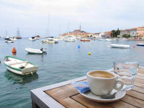 cup of coffe and glass of water with a horizontal view of the port in Porec the old Croatian Adriatic town of Croatia.