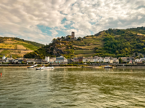 Traveling along the Rhine River with scenic views of the quaint town of Oberwesel, Germany. Views of European style architecture and agricultural fields on the sloping land. Oberwesel is a medieval town in Germany located on the Middle Rhine.