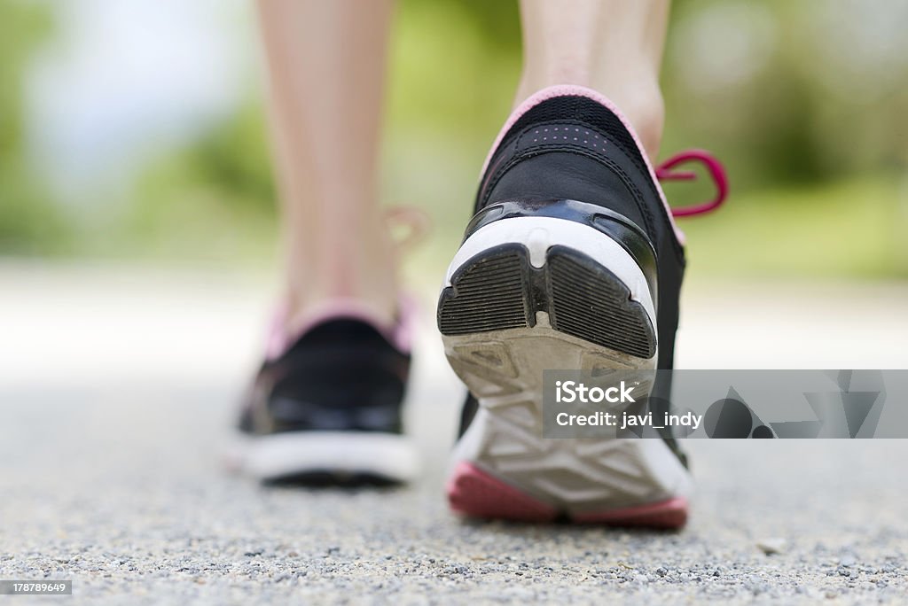 Woman feet running on road closeup trainers Woman feet running on road closeup on shoe Active Lifestyle Stock Photo