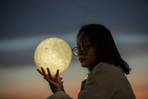 istock Pretty young woman is playing with a moon shaped artificial lamp at sunset. 1787897308